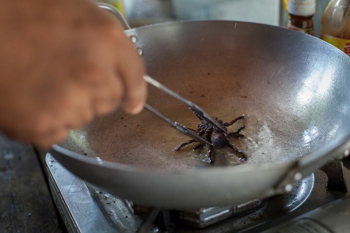 Шеф-повар ресторана готовит тарантула для посетителей